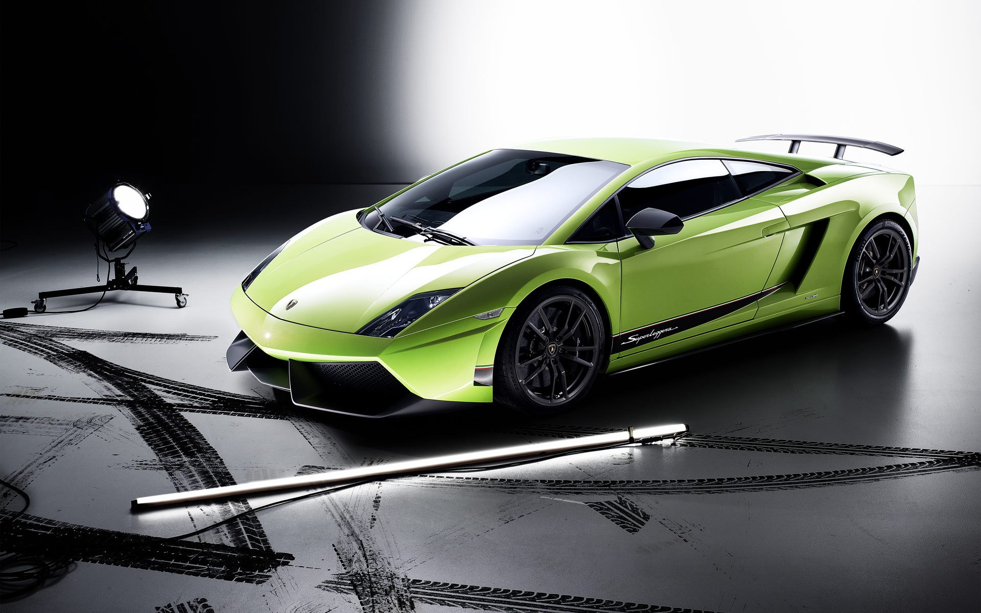 HD PC desktop wallpaper featuring a vibrant green Lamborghini Gallardo Superleggera in a sleek studio setting with dramatic lighting and tire marks on the floor.