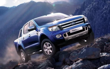 A Ford Ranger off-roading over rocky terrain, showcasing its rugged design against a backdrop of mountains and sunlight, capturing the spirit of adventure in an HD desktop wallpaper.