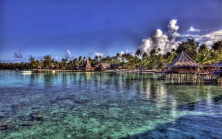 A tranquil tropical scene featuring a thatched hut by the clear blue ocean, surrounded by lush palm trees and vibrant skies, captured in stunning HDR photography.