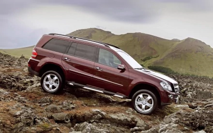 HD desktop wallpaper featuring a maroon Mercedes SUV navigating rocky terrain with hills in the background.