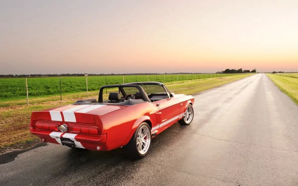 A stunning Shelby GT500 Classic Recreation in vibrant red parked on an open road, showcasing its classic muscle car design against a beautiful sunset backdrop.