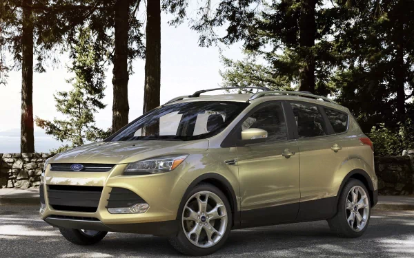 HD PC desktop wallpaper showing a gold Ford Escape SUV parked on a sunlit forest road with tall trees and a lake visible in the background.