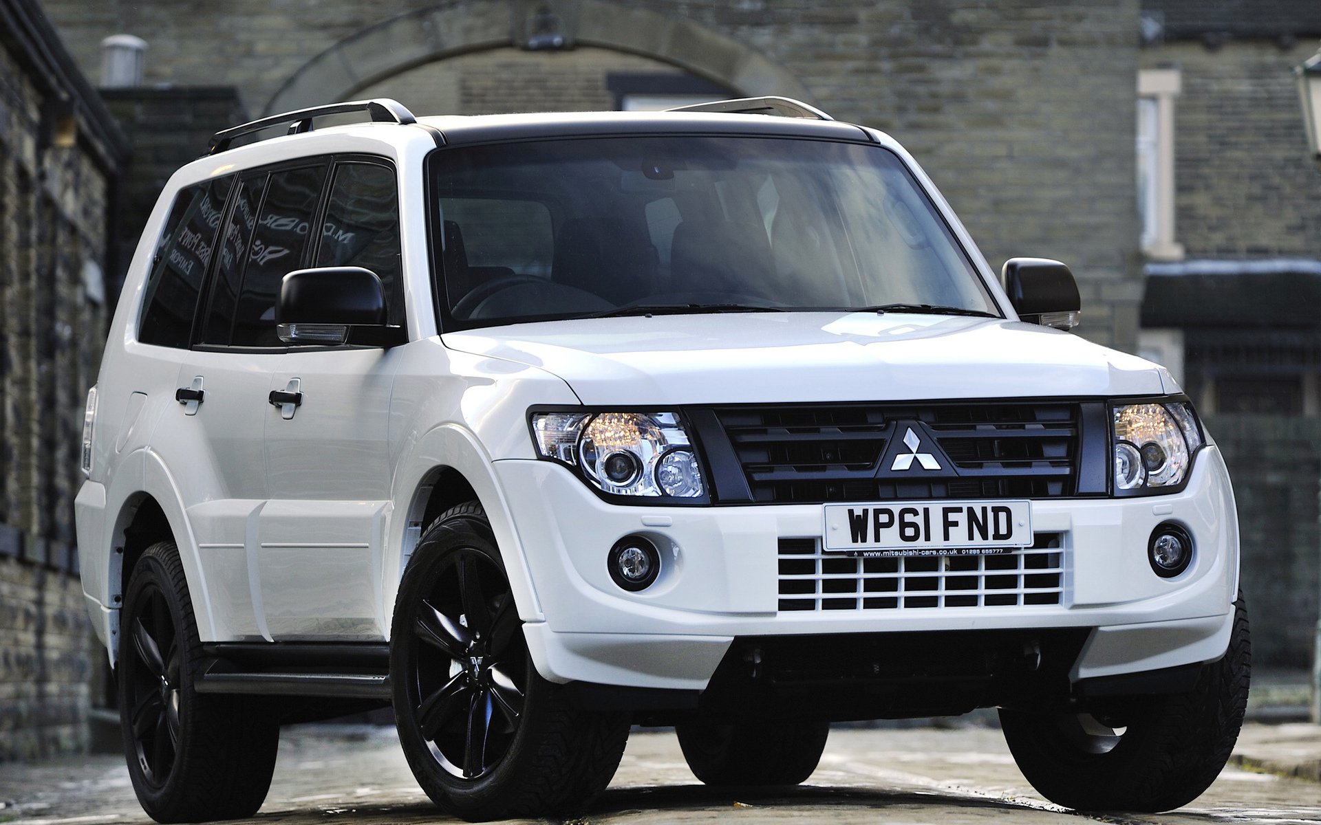 HD PC desktop wallpaper and background: white Mitsubishi SUV parked on an urban street, front three-quarter view with black wheels.
