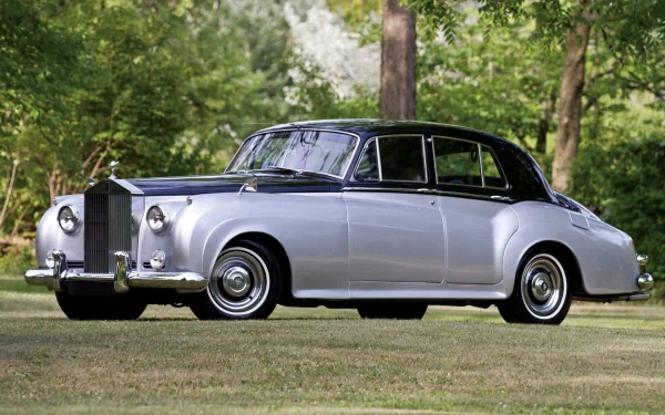 HD desktop wallpaper featuring a classic silver Rolls-Royce car parked on grass with trees in the background, showcasing timeless luxury and elegance.
