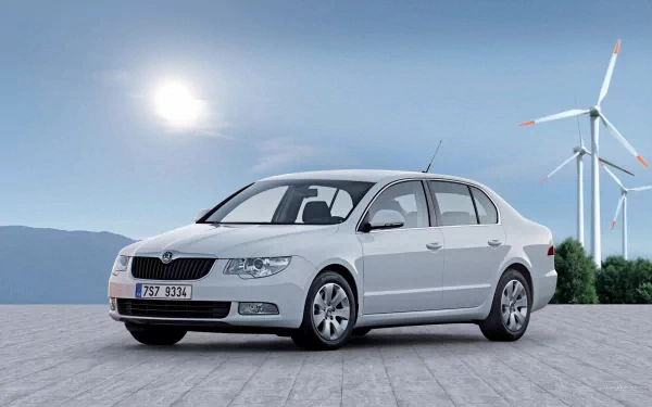 HD PC desktop wallpaper featuring a white Skoda vehicle parked on a paved surface with wind turbines and mountains under a bright sky in the background.