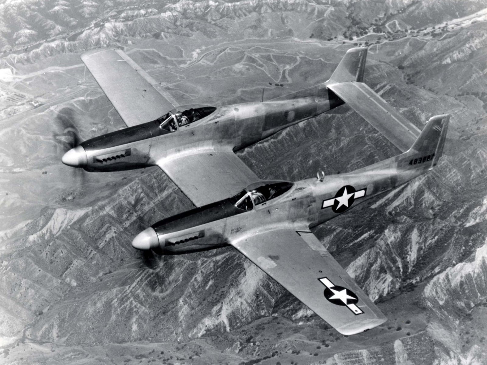 Black-and-white image of a North American F-82 Twin Mustang military aircraft flying over mountainous terrain as an HD PC desktop wallpaper and background.