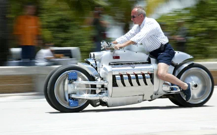 Rider on a silver Dodge Tomahawk motorcycle speeding past palm trees; dynamic motion blur, HD PC desktop wallpaper background.