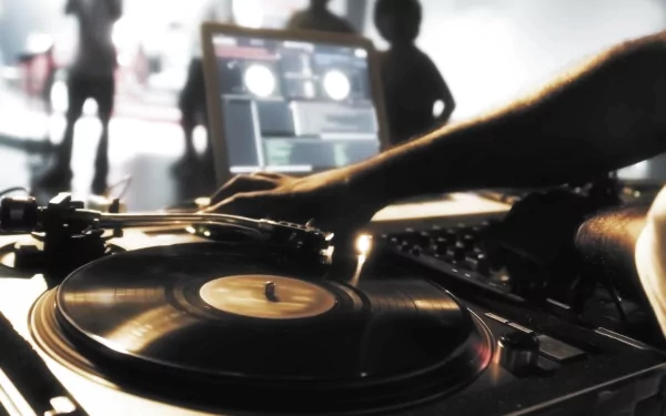 A dynamic DJ scene featuring a hand on a turntable, set against a vibrant background with silhouettes of people enjoying music, creates an engaging HD desktop wallpaper.