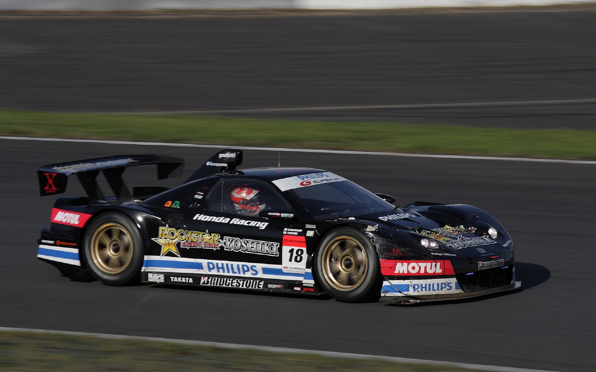 High-speed Honda race vehicle with sponsor livery on a racetrack, rendered as a 2K Quad HD PC desktop wallpaper/background.