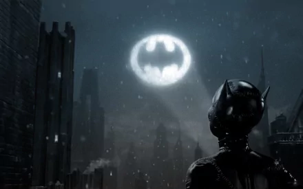 HD comic-style desktop wallpaper featuring Catwoman overlooking a dark cityscape with the illuminated Batman symbol in the cloudy night sky.