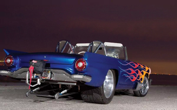 HD desktop wallpaper featuring a classic blue Ford Thunderbird with flame decals and a drag racing setup under a dark sky background.