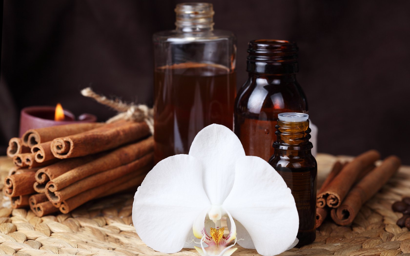 HD PC desktop wallpaper featuring food-themed herbs and spices, including cinnamon sticks, essential oil bottles, and a white orchid on a woven surface.