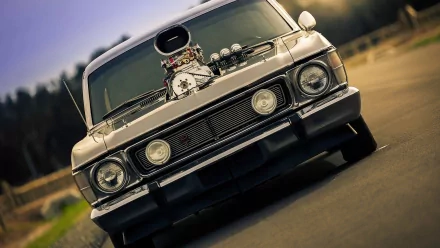 HD desktop wallpaper featuring a close-up front view of a customized Ford Cortina with a powerful engine exposed through the hood, set against a blurred outdoor background.