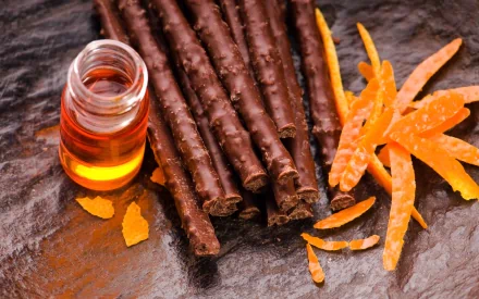 HD desktop wallpaper featuring aromatic herbs and spices including cinnamon sticks, orange peels, and a small bottle of amber-colored liquid on a textured surface.