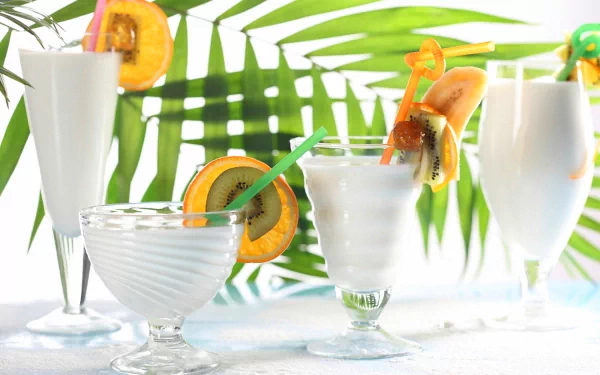 HD PC desktop wallpaper featuring a refreshing assortment of white cocktails garnished with citrus slices against a vibrant green palm leaf background.