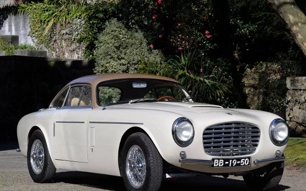 HD PC desktop wallpaper of a white Siata vehicle parked by a stone wall and lush garden, front three-quarter view showcasing chrome grille, round headlights and wire-spoke wheels.