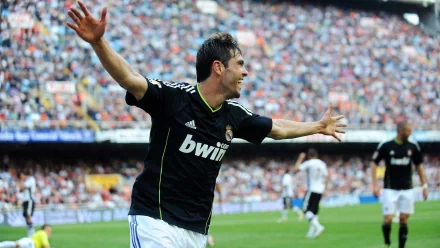 HD desktop wallpaper of Kaká celebrating a goal in a black Real Madrid C.F. jersey during a vibrant football match with a packed stadium background.