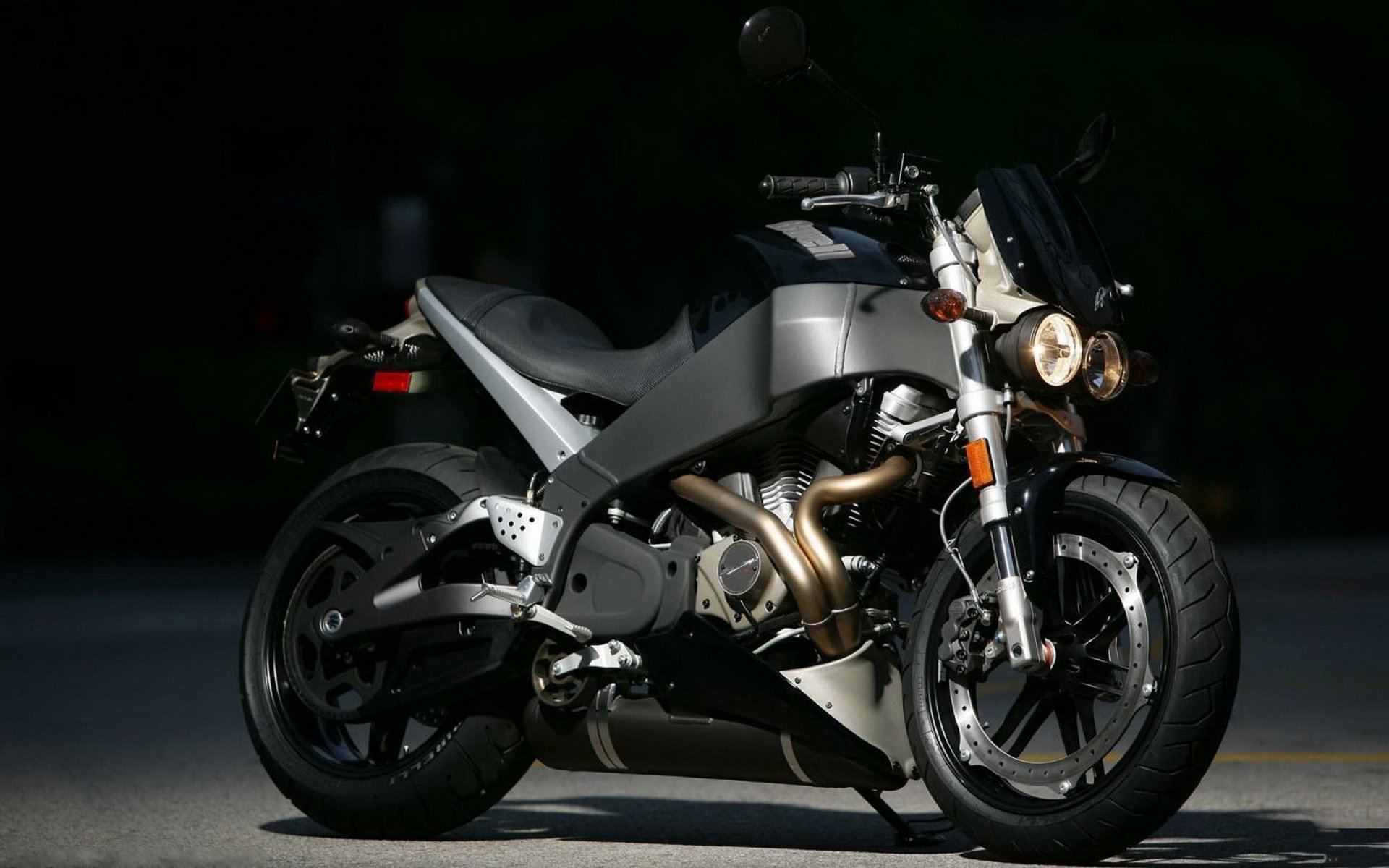 HD PC desktop wallpaper of a sleek gray Buell sport motorcycle parked against a dark backdrop, spotlight highlighting its frame and exposed engine.