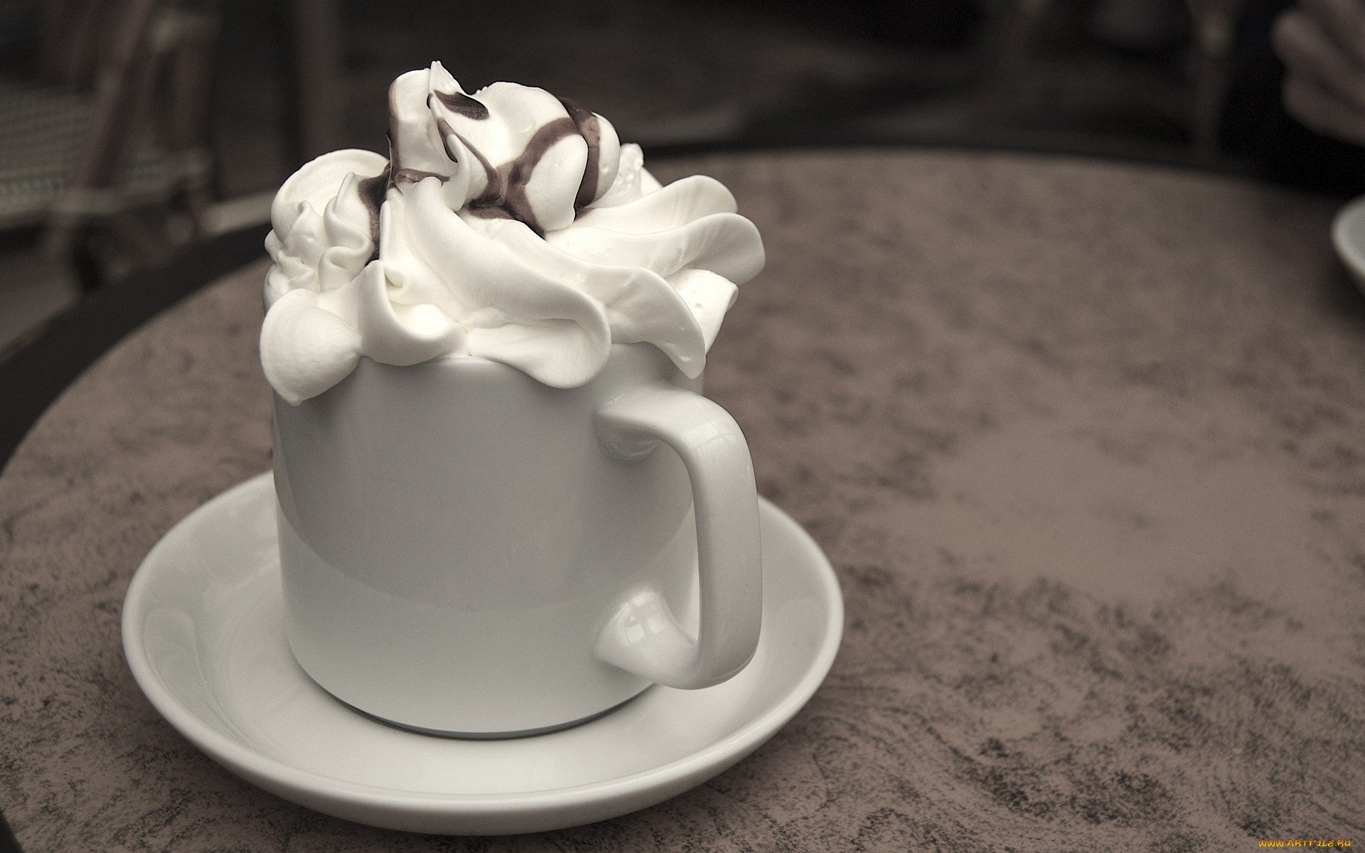 HD desktop wallpaper featuring a close-up of a coffee cup topped with swirls of creamy whipped cream on a saucer, set on a textured table.