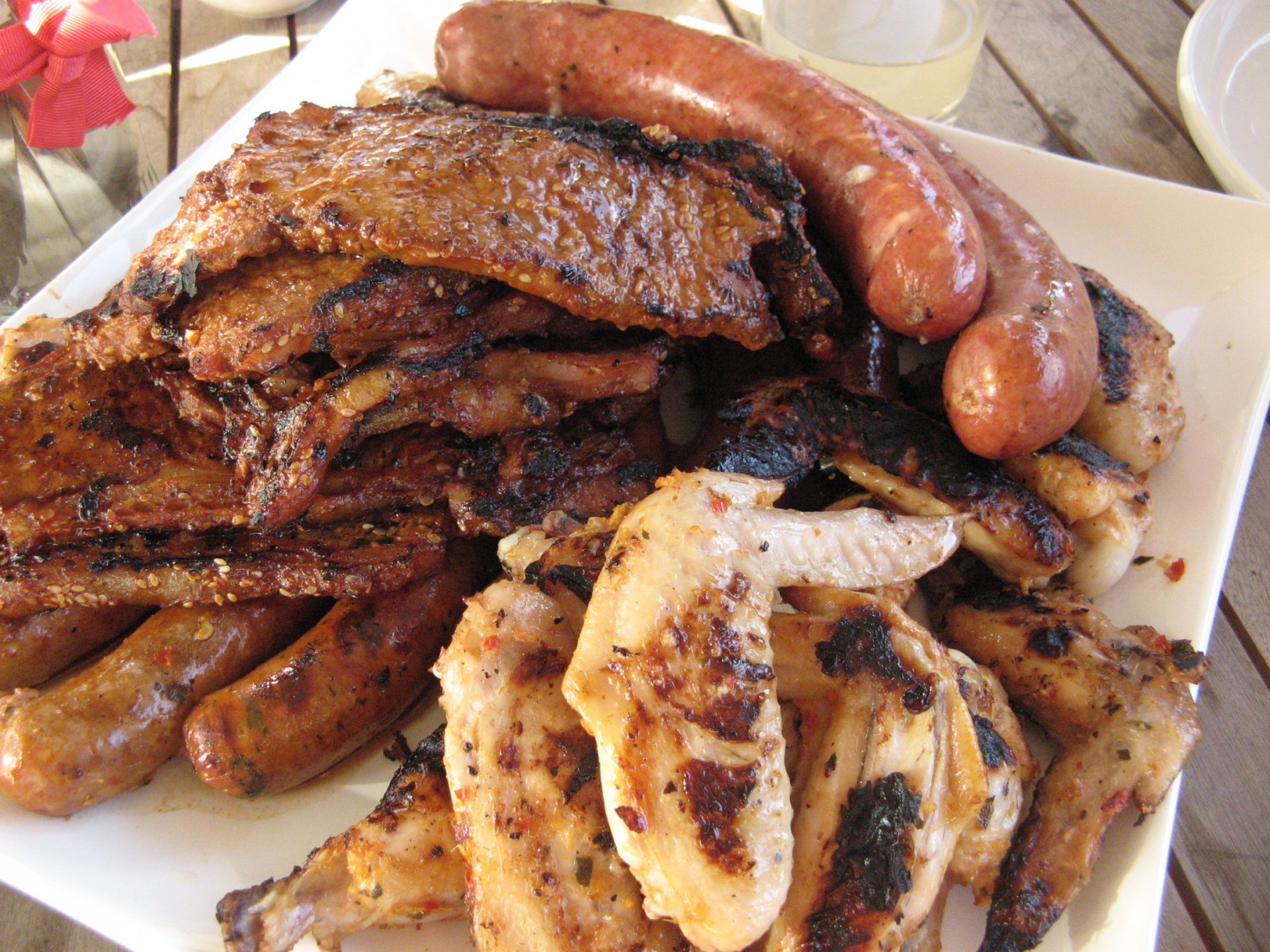 Food/meat HD PC desktop wallpaper: close-up platter of assorted grilled meats — charred ribs, sausages and sliced chicken.