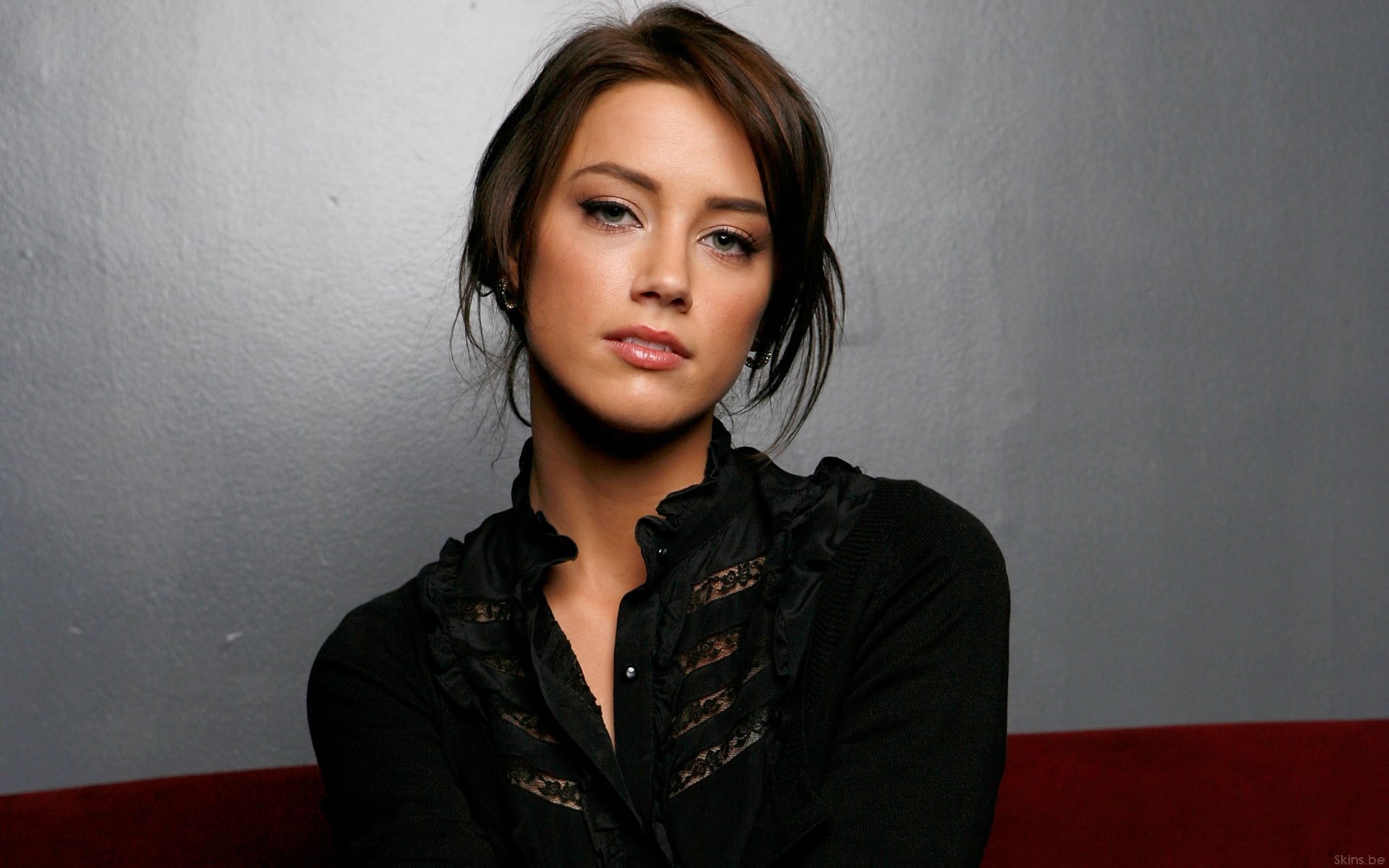 HD desktop wallpaper featuring celebrity Amber Heard against a neutral gray background, dressed in a black top with lace accents.