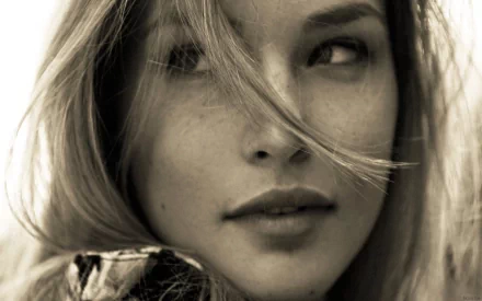 HD PC desktop wallpaper: close-up sepia portrait of a celebrity model with windblown hair, subtle freckles and a soft, contemplative expression.