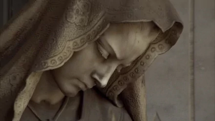 HD desktop wallpaper featuring a close-up of a man-made statue depicting a solemn, hooded figure with intricate carved details.