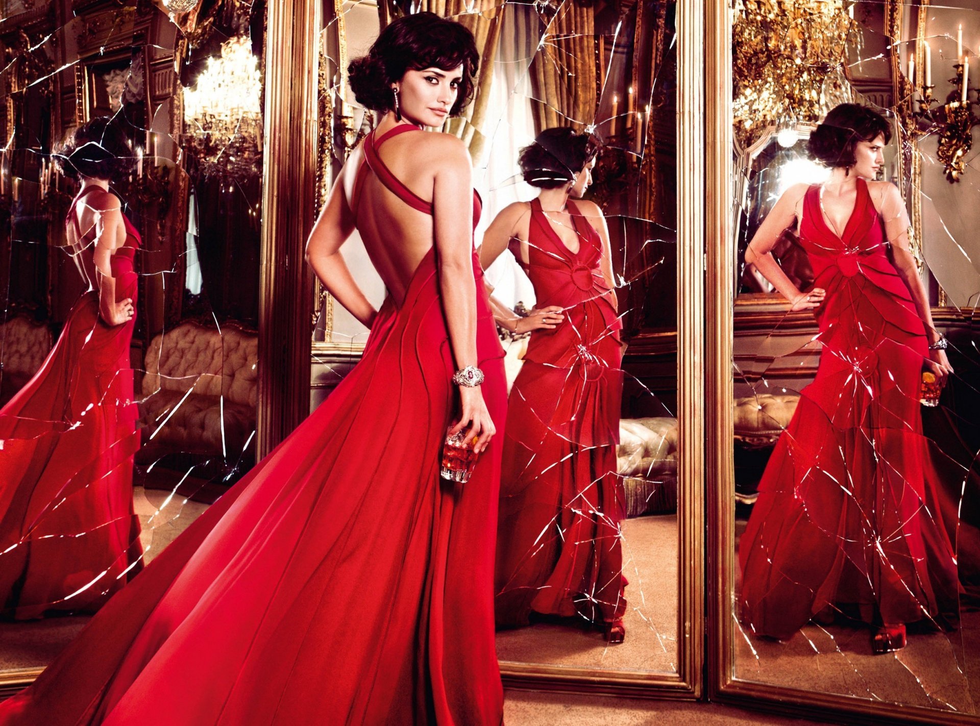 A stunning image of Penelope Cruz in a flowing red gown, surrounded by mirrors, showcasing her elegance and glamour. This HD wallpaper captures a captivating moment.