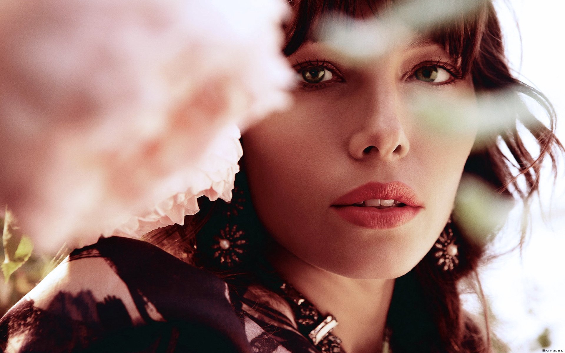 Close-up of Jessica Biel, showcasing her striking features against a blurred floral background. This HD wallpaper captures her elegance and beauty in a vibrant setting.