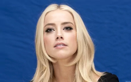 HD desktop wallpaper featuring Amber Heard, a celebrity with blonde hair and striking features, set against a vivid blue background.