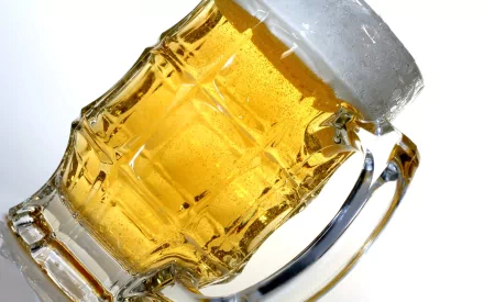 HD desktop wallpaper featuring a close-up of a frosty mug filled with golden beer, highlighting its cold condensation and rich amber color against a white background.