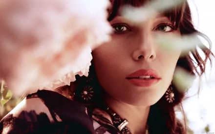 Close-up of Jessica Biel, showcasing her striking features against a blurred floral background. This HD wallpaper captures her elegance and beauty in a vibrant setting.