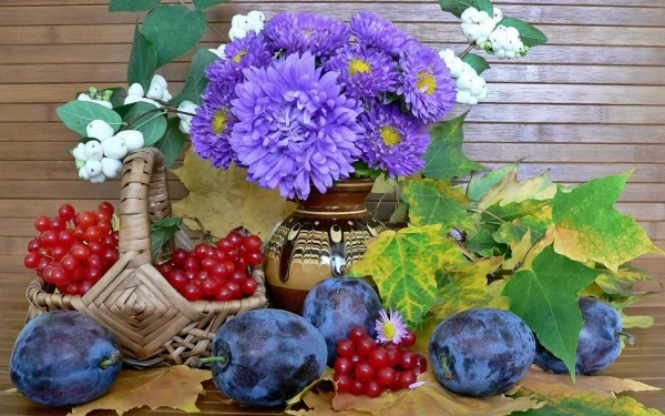 HD desktop wallpaper featuring a still life arrangement of purple flowers, plums, red berries, and green leaves on a wooden surface.