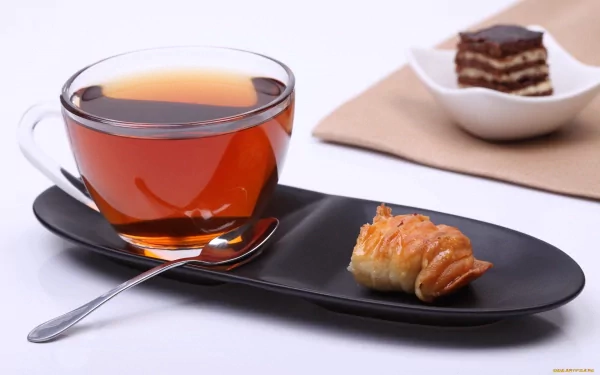 HD PC desktop wallpaper featuring a clear glass cup of tea with a croissant on a black tray, and a slice of layered dessert in the background. Food and tea theme.