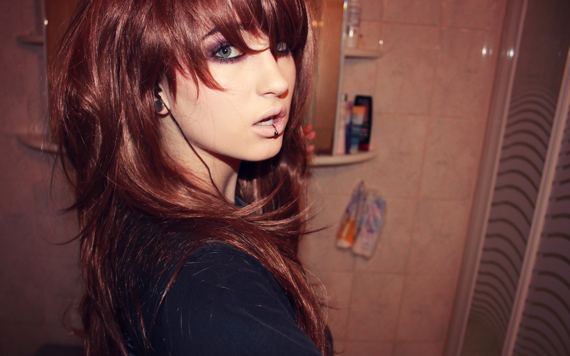 A woman with striking features and long, layered hair poses in a bathroom setting. This HD image serves as a captivating PC desktop wallpaper and background.