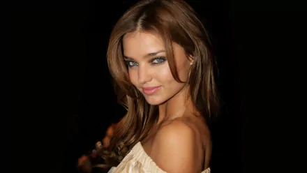 HD desktop wallpaper featuring a close-up of celebrity model Miranda Kerr with a charming smile and soft lighting against a dark background.