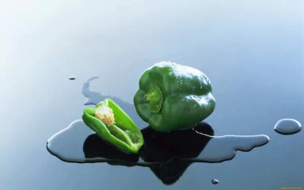 HD desktop wallpaper featuring a glossy green bell pepper, whole and halved, resting on a reflective surface with water droplets.
