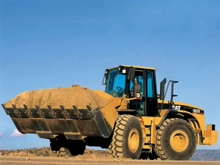 HD desktop wallpaper of a Caterpillar Inc. heavy-duty vehicle lifting a large load of sand under a clear blue sky.