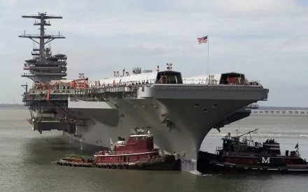 USS George H.W. Bush (CVN-77) aircraft carrier docked, with tugboats alongside, set against a cloudy sky as a HD military warship desktop wallpaper.