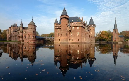A stunning HD image of Castle De Haar, showcasing its impressive architecture reflected in the calm waters surrounding it. The scene captures the beauty of this man-made landmark.