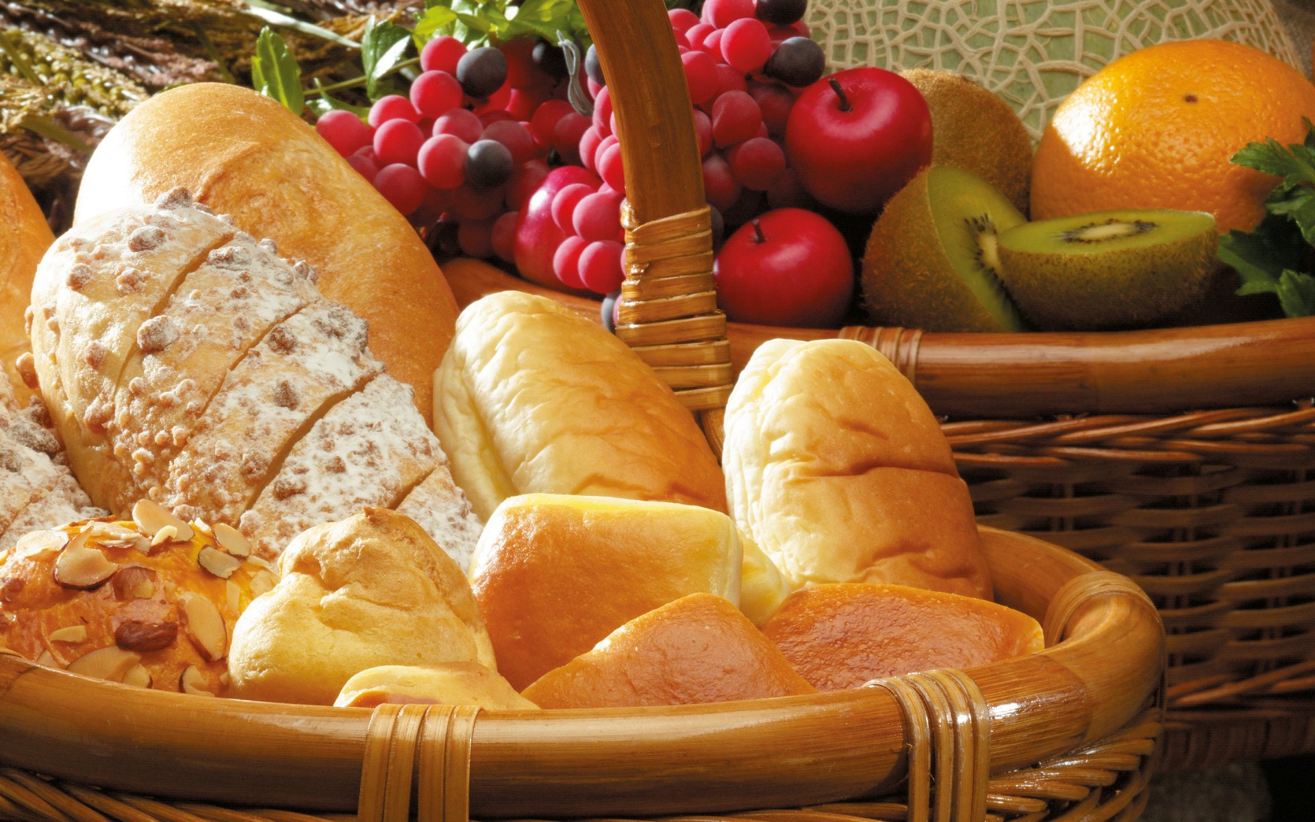 HD desktop wallpaper showing an assortment of freshly baked breads and a basket of assorted fruits highlighting food and baking themes.