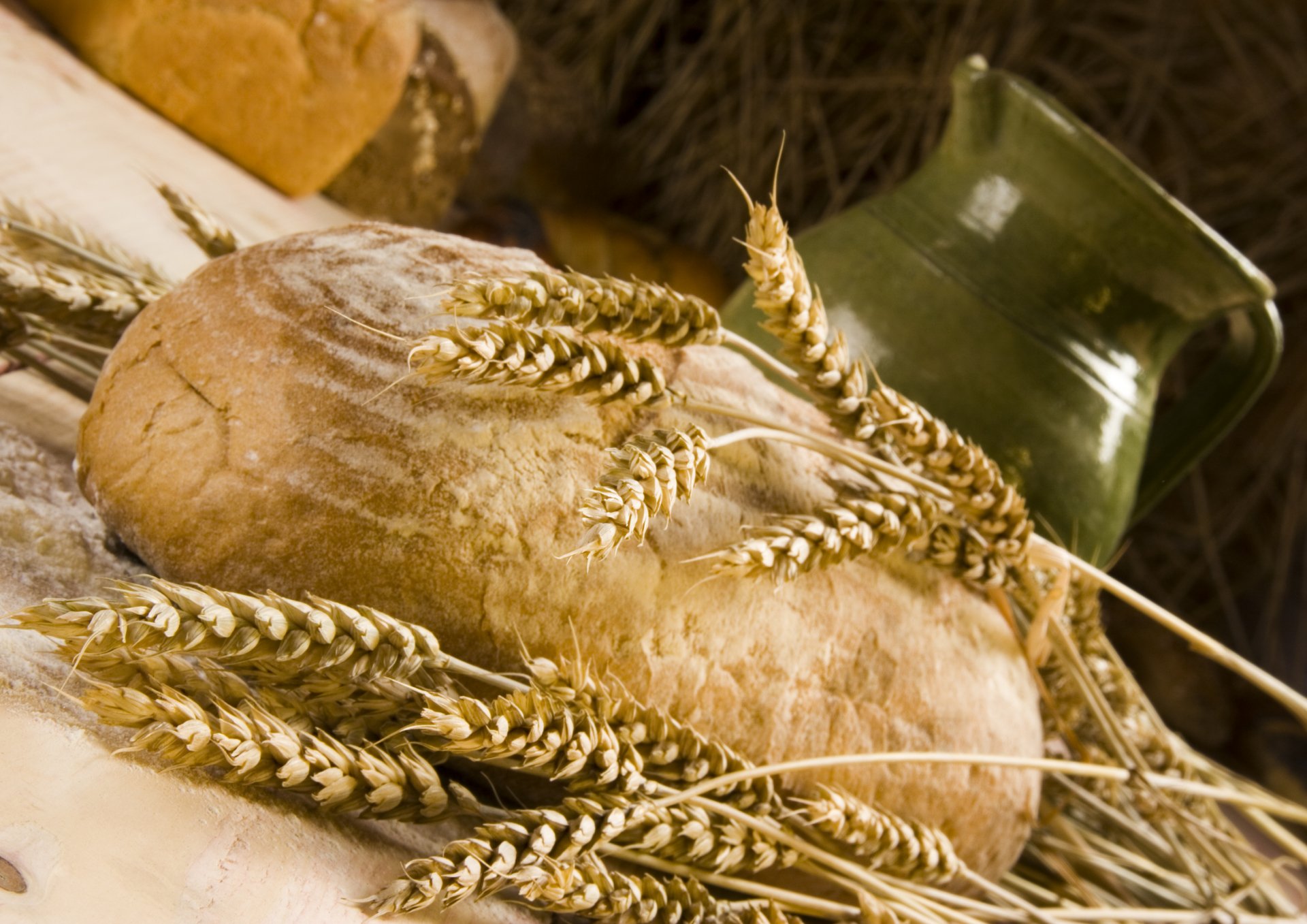 HD PC desktop wallpaper featuring rustic bread surrounded by wheat stalks and a vintage green ceramic jug, highlighting food and bread themes.