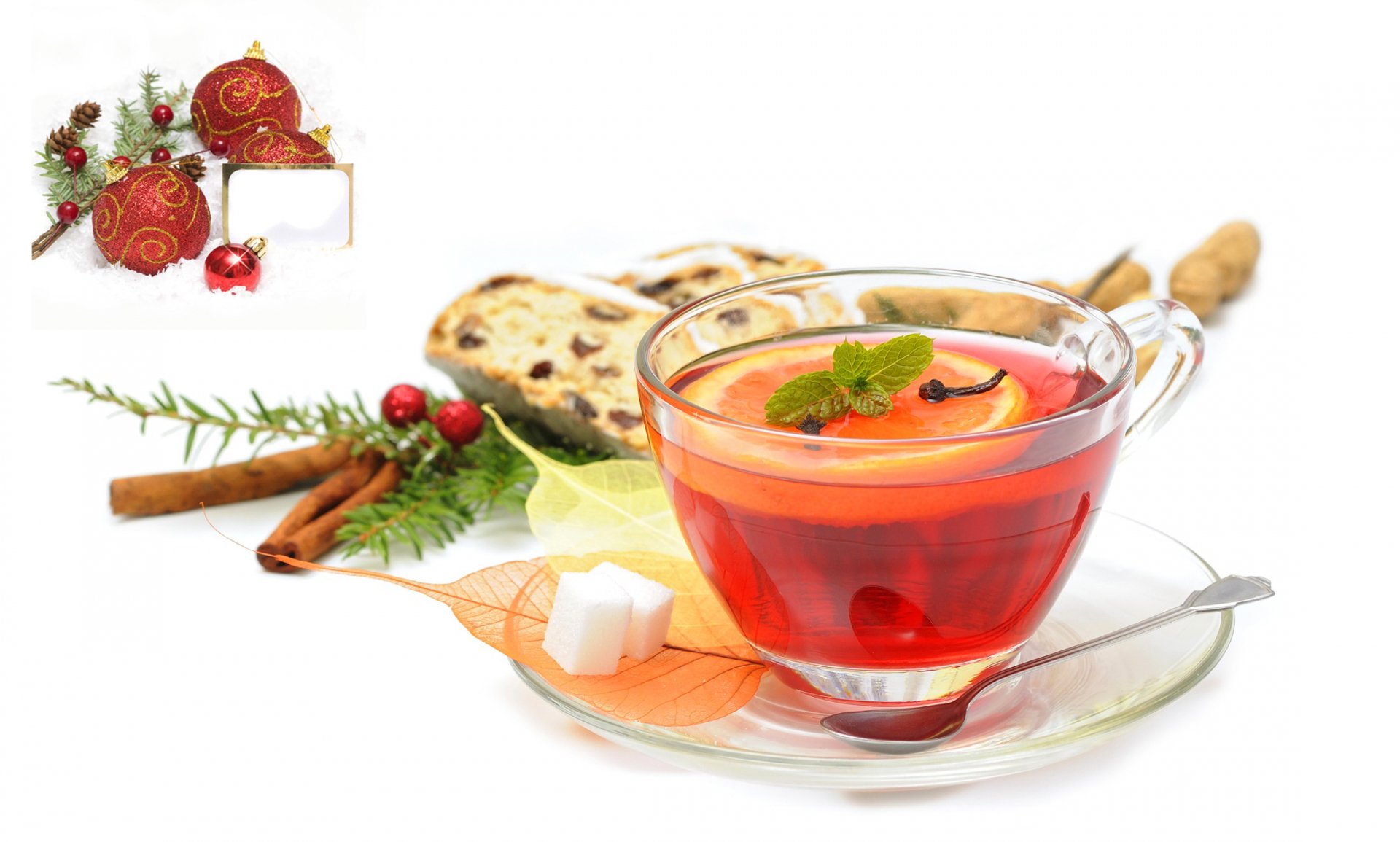 HD PC desktop wallpaper featuring a clear glass cup of red tea garnished with mint, accompanied by cinnamon sticks, sugar cubes, and festive holiday decorations.