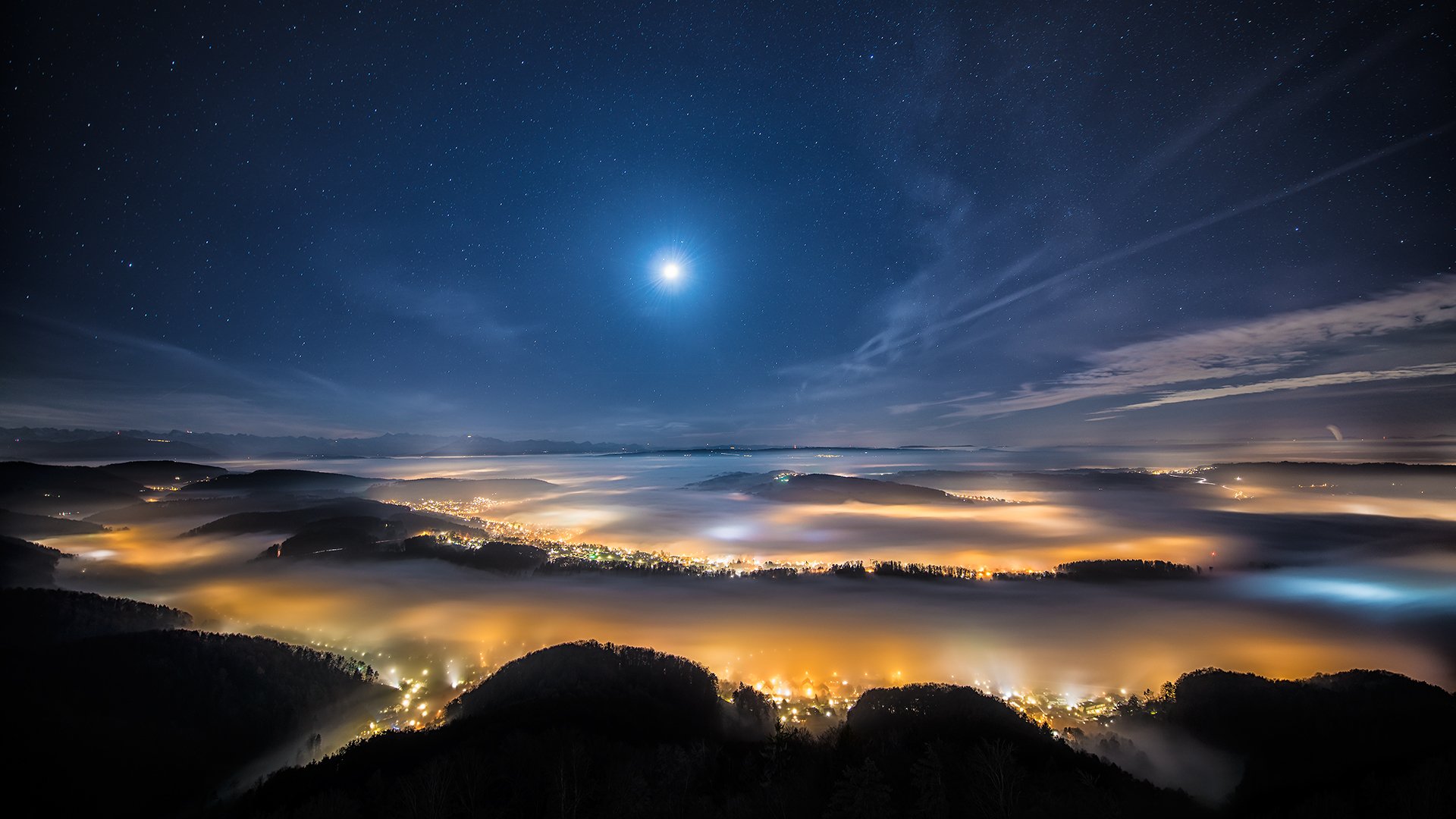 HD scenic photography of a night sky with a bright moon over illuminated hills and mist-covered valleys, designed as a PC desktop wallpaper and background.