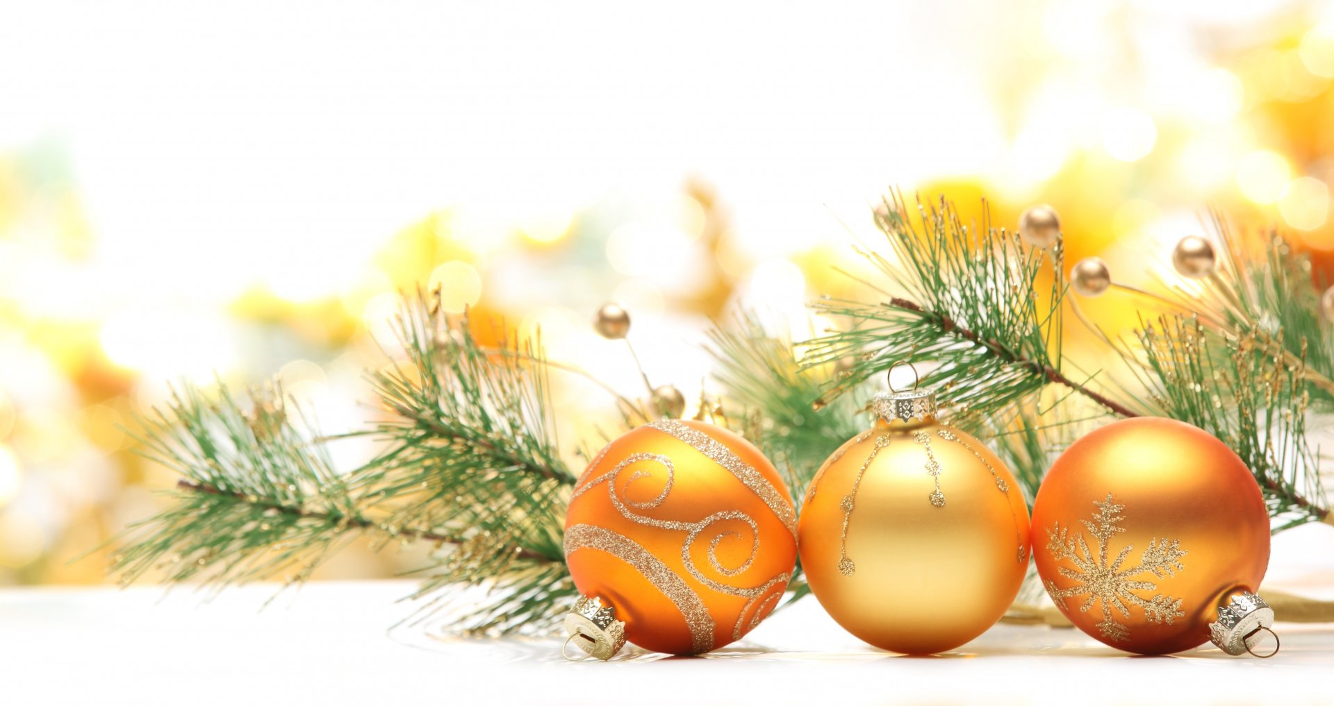 A vibrant 4K Ultra HD Christmas desktop wallpaper featuring golden holiday ornaments resting on festive pine branches with a soft, glowing background.
