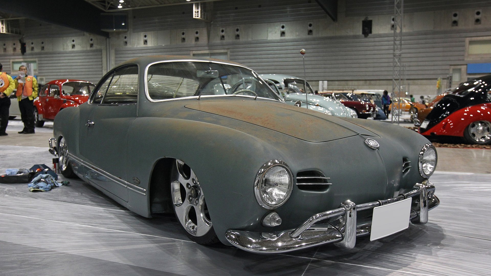 HD PC desktop wallpaper featuring a sleek, matte-finished Volkswagen classic car showcased indoors at an auto exhibition.