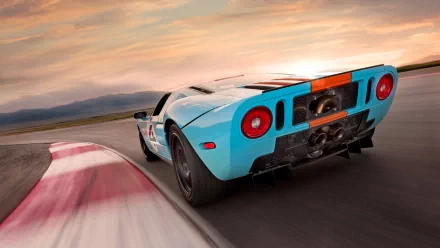 HD PC desktop wallpaper featuring a dynamic rear view of a blue Ford GT40 racing on a track at sunset.
