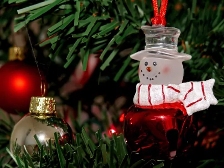 HD PC desktop wallpaper featuring detailed Christmas ornaments, including a glass snowman and festive baubles, set against green holiday tree branches.