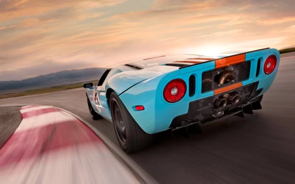 HD PC desktop wallpaper featuring a dynamic rear view of a blue Ford GT40 racing on a track at sunset.