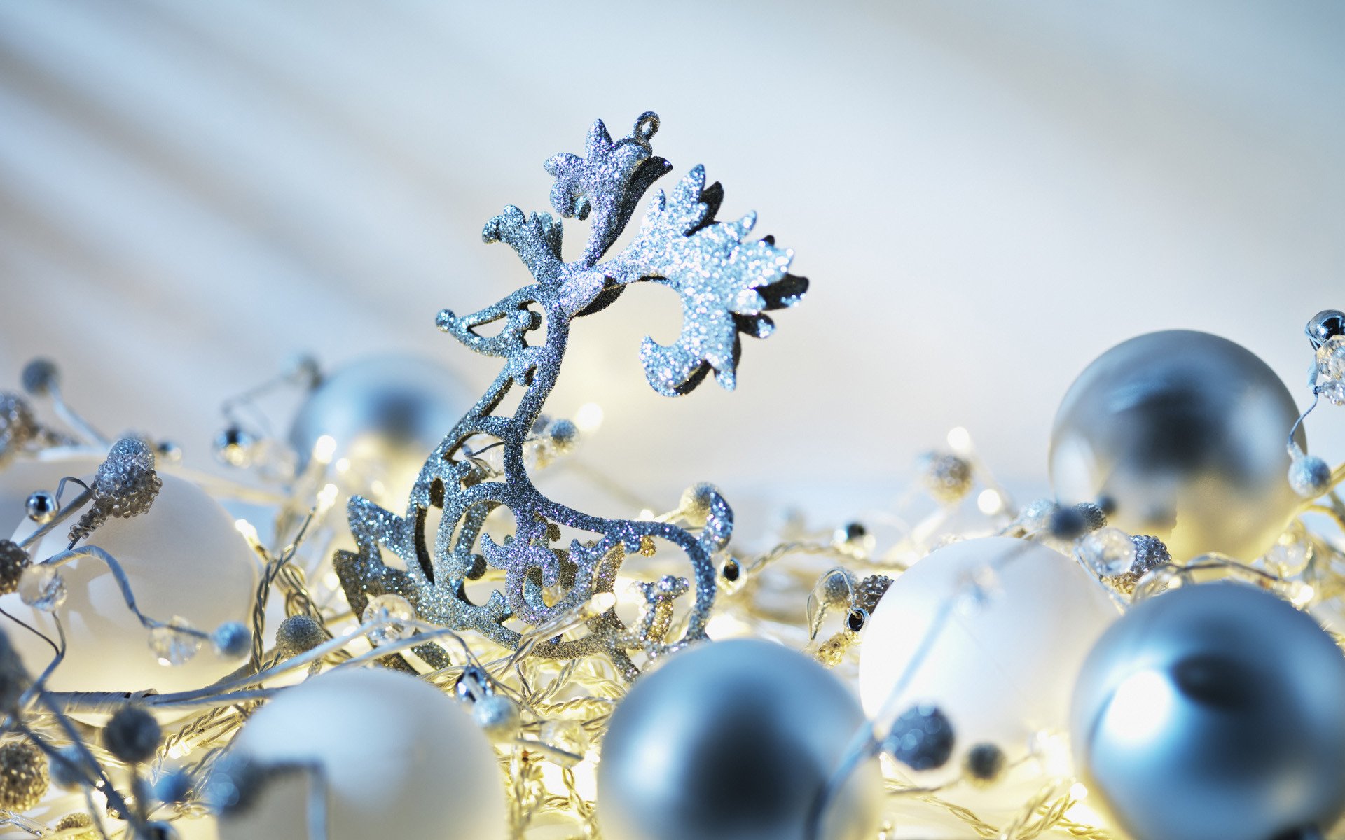 A sparkling reindeer ornament surrounded by shimmering silver and white Christmas decorations, illuminated by soft, warm lights, creating a festive holiday atmosphere.